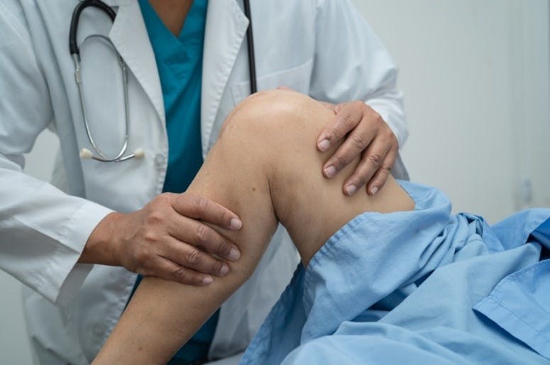Orthopedic physician examining a patient after total knee replacement